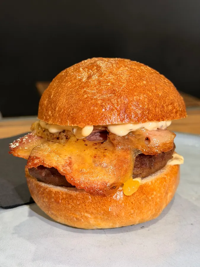 Angus beef burger with bacon and cheese on a milk bun