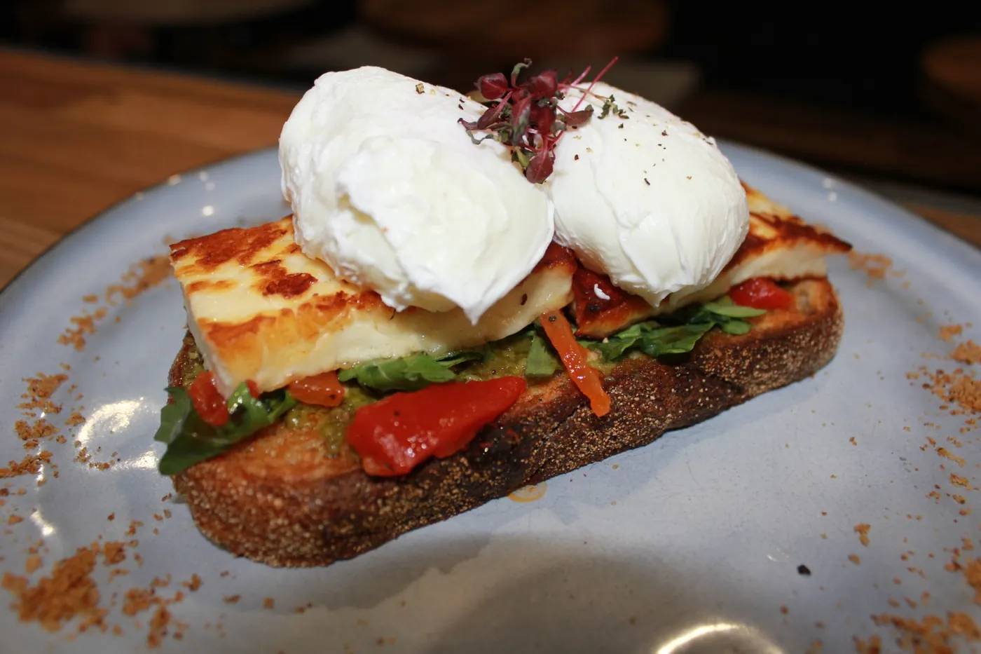 Two poached eggs on grilled halloumi, capsicum and rocket on toasted sourdough