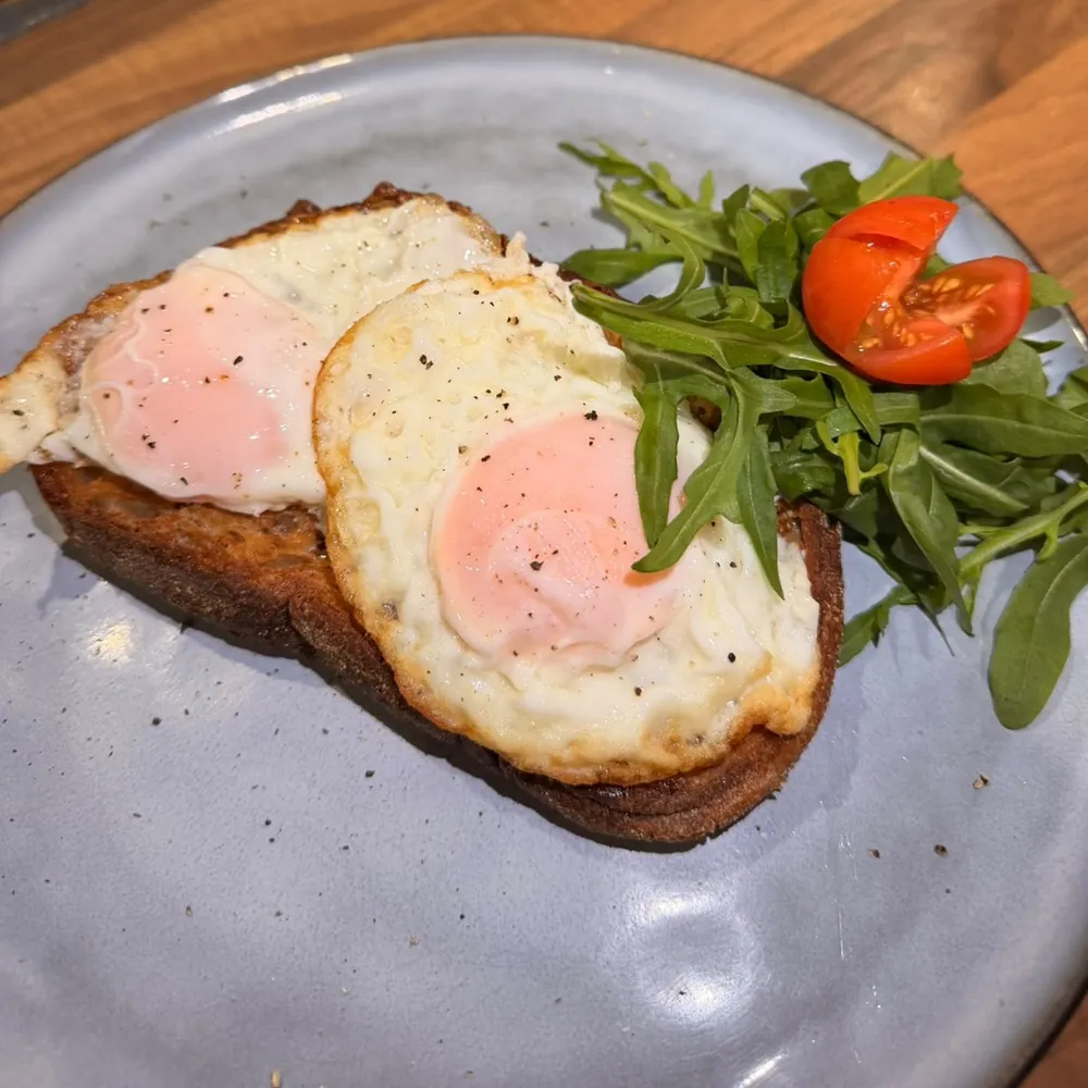 Two fried eggs on toasted sourdough with rocket and cherry tomato