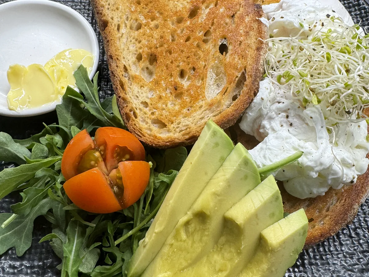 Poached eggs on toasted sourdough with avocado, tomato and rocket