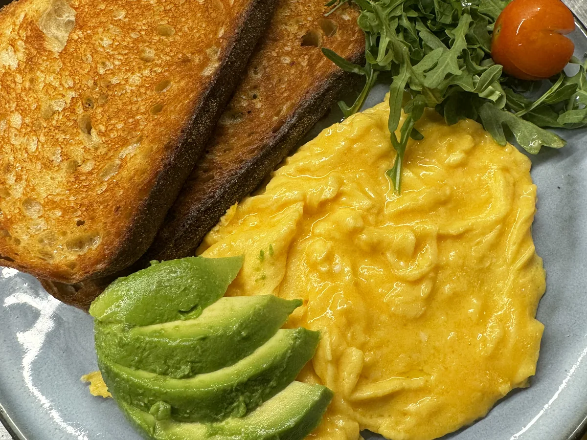 Scrambled eggs on toasted sourdough with avocado and rocket