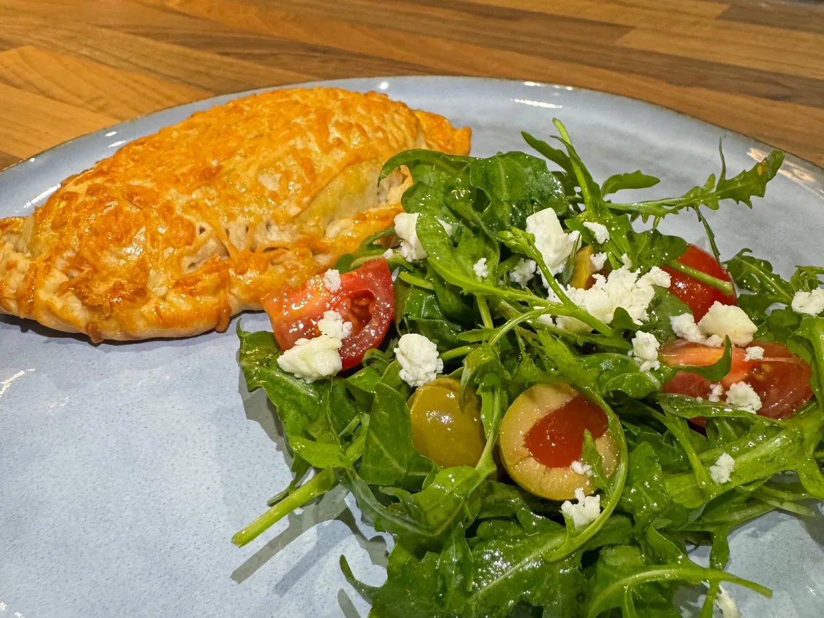 An empanada served with a rocket, tomato and feta salad