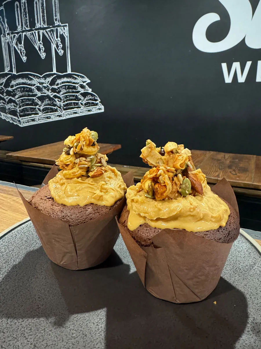 Two peanut butter muffins topped with granola, on a table at Silo West