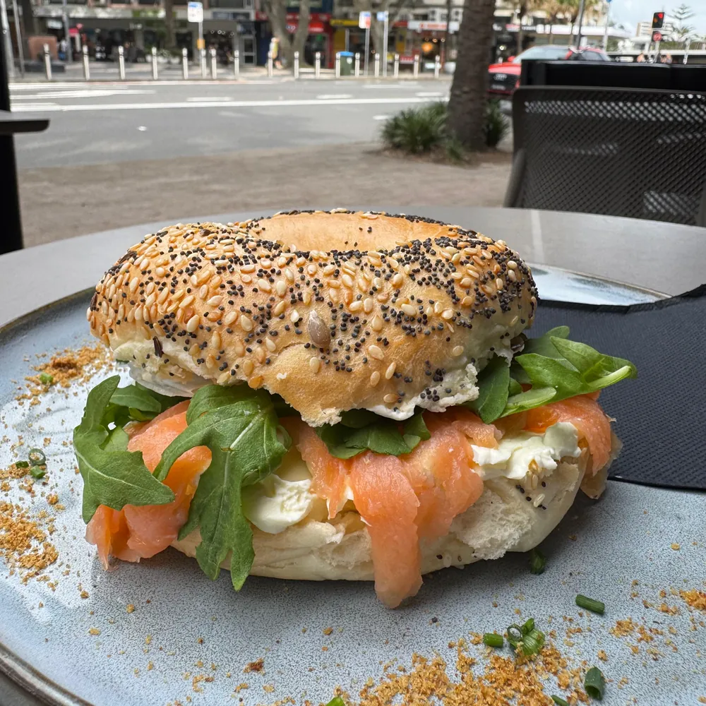 A seeded bagel filled with smoked salmon, cream cheese and rocket