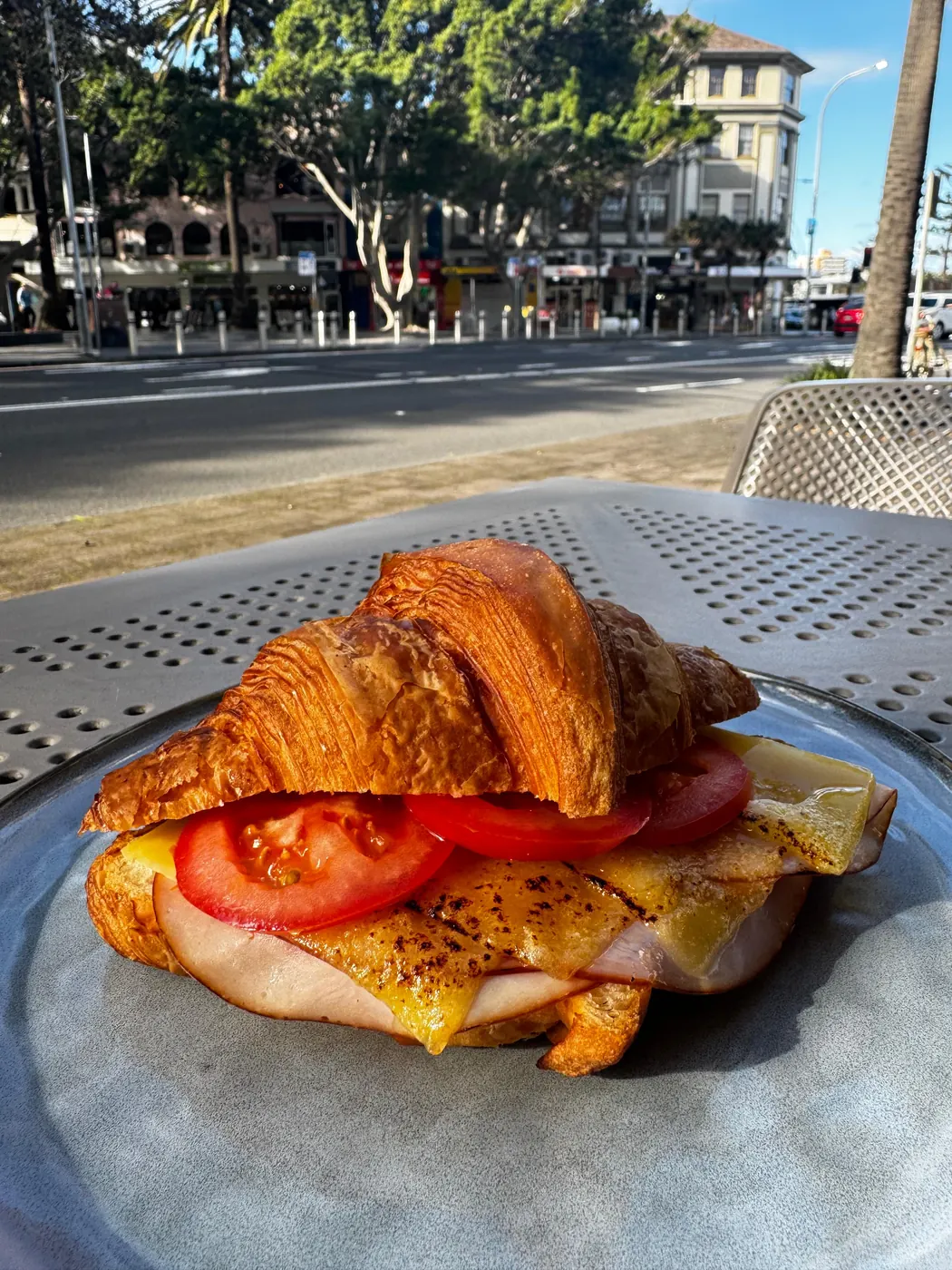 A croissant filled with ham and cheese, on a table outside Silo West