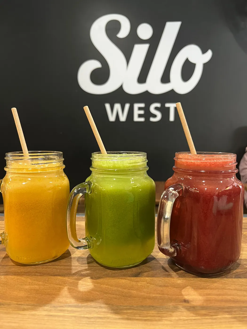 Three fresh juices on the bench under the Silo West sign
