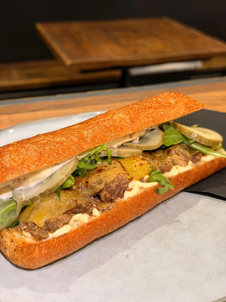 Truffle brisket sandwich with cheese, pickled cucumber and rocket on panini