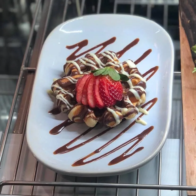 A waffle with strawberries and chocolate sauce